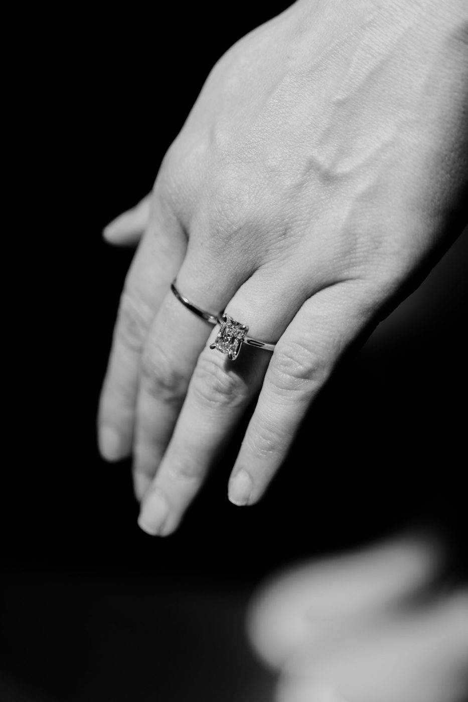 Black-and-white close-up of a hand wearing a radiant-cut solitaire