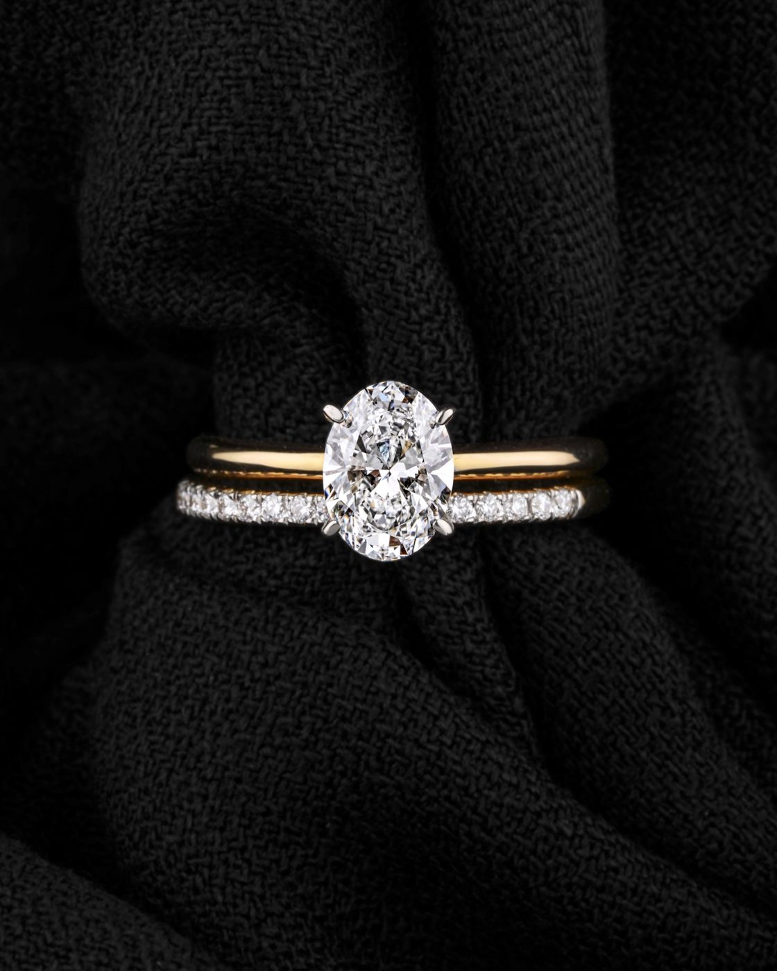 Oval diamond solitaire in yellow gold stacked with a pavé band