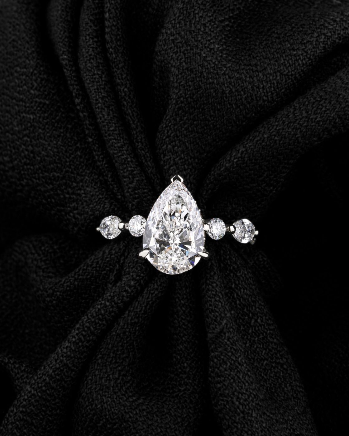 Pear diamond with round side stones in white gold