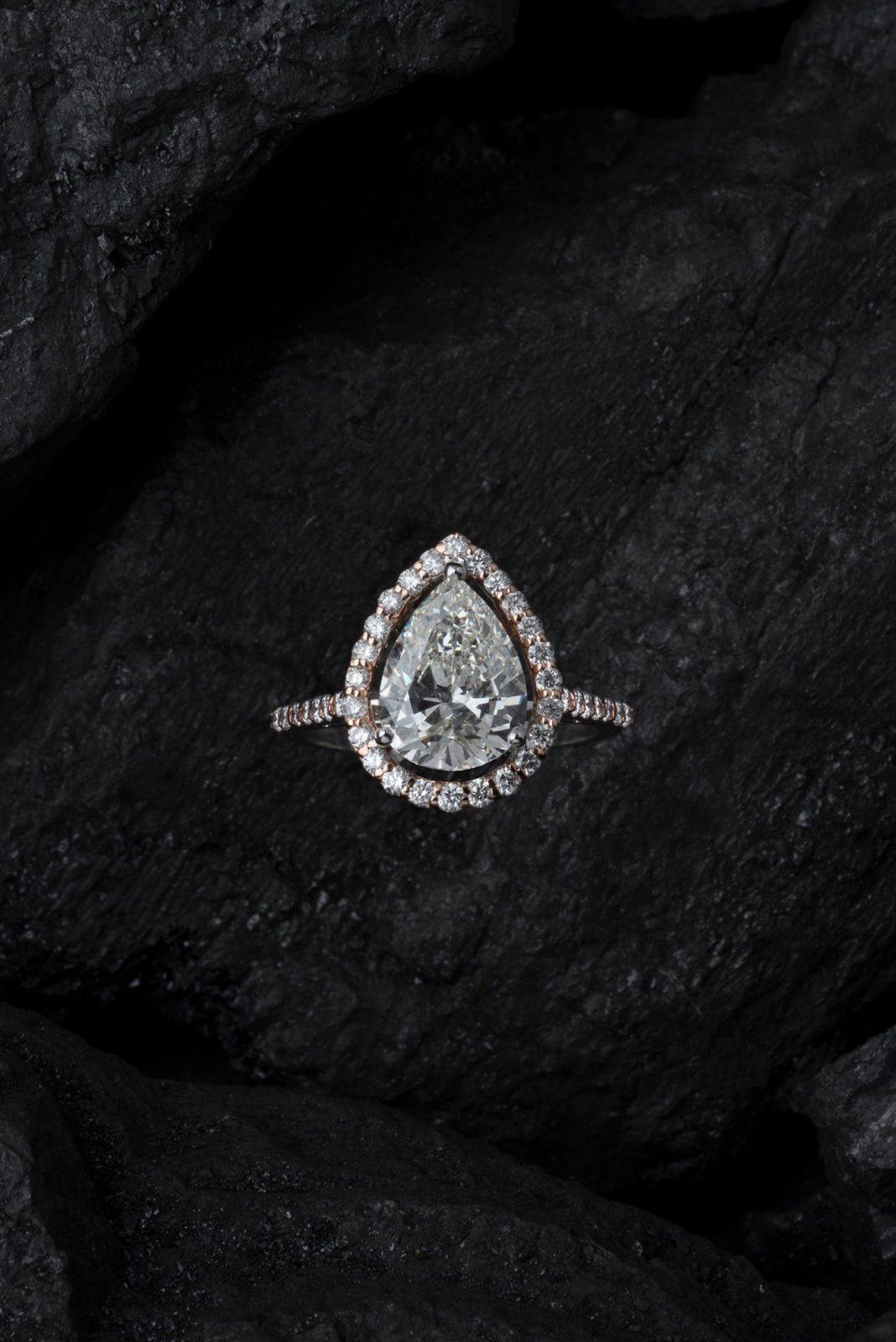 Pear-shaped diamond halo ring in rose gold on dark stone