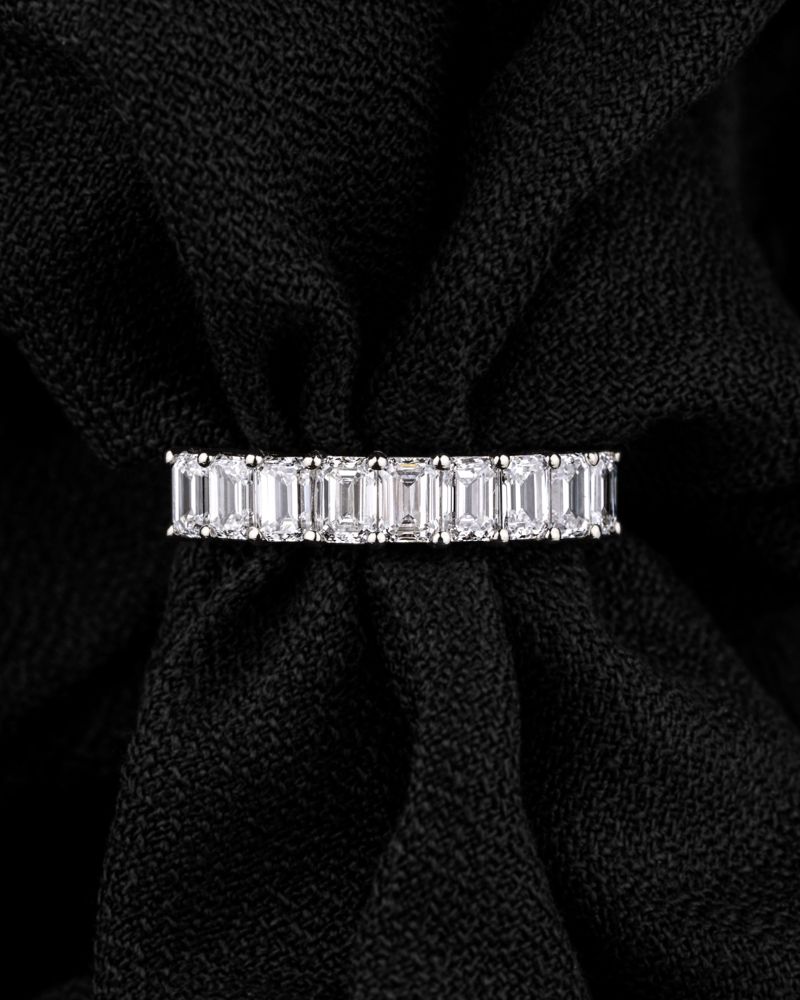 Emerald-cut diamond eternity band in platinum on black fabric