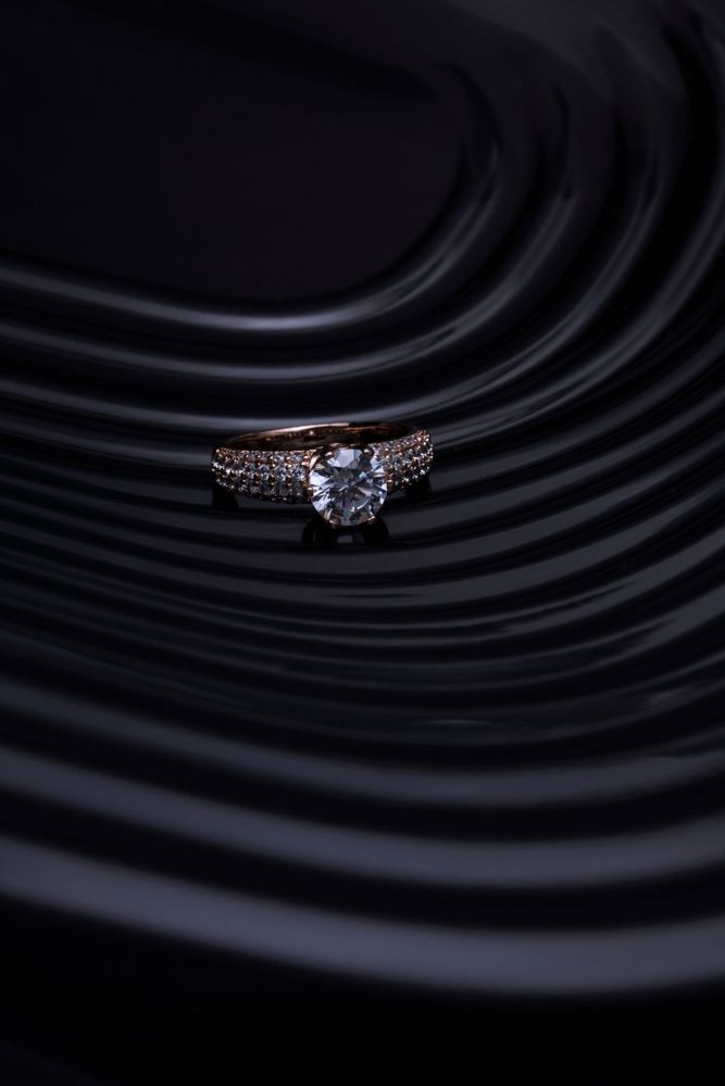 Round diamond solitaire in rose gold with three rows of pavé on the shoulders