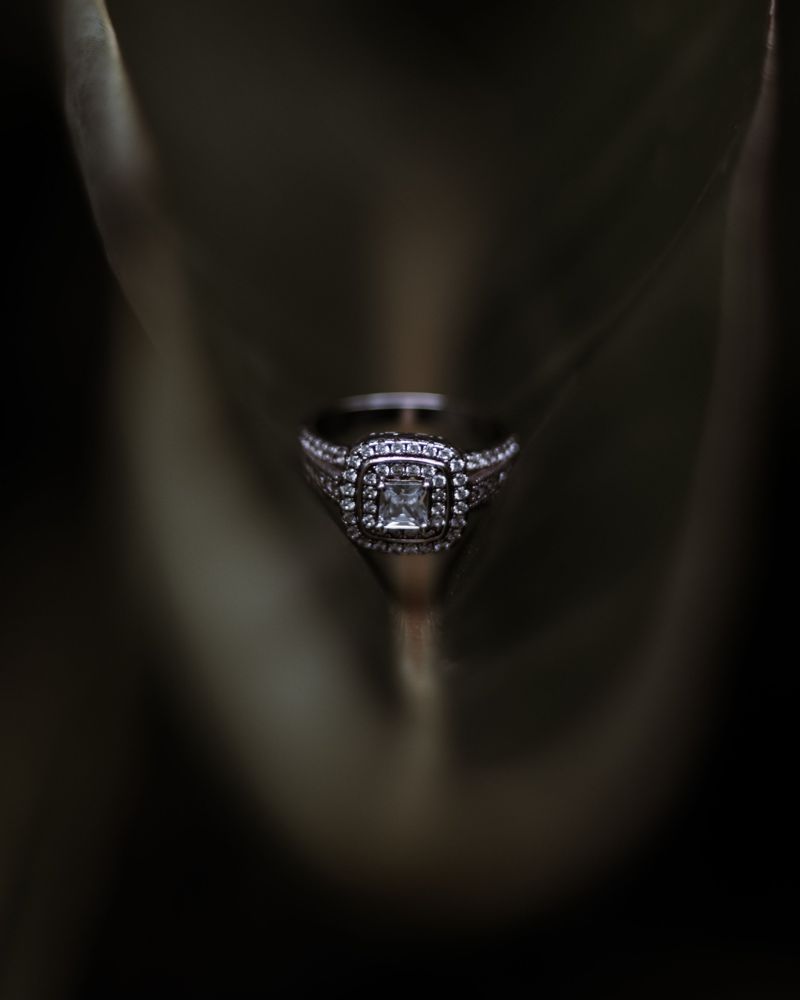 Princess-cut diamond in a double halo with a pavé band in white gold