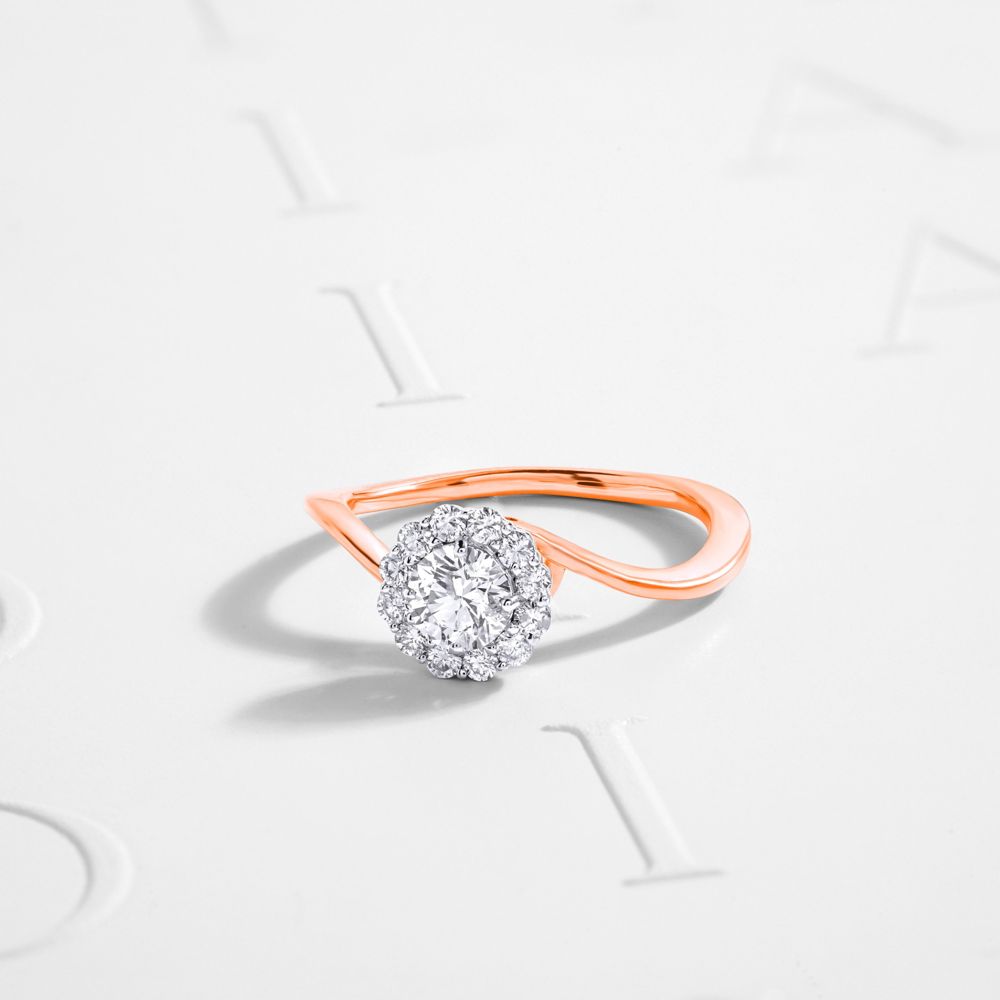 Round diamond in a floral halo on a curved bypass band in rose gold