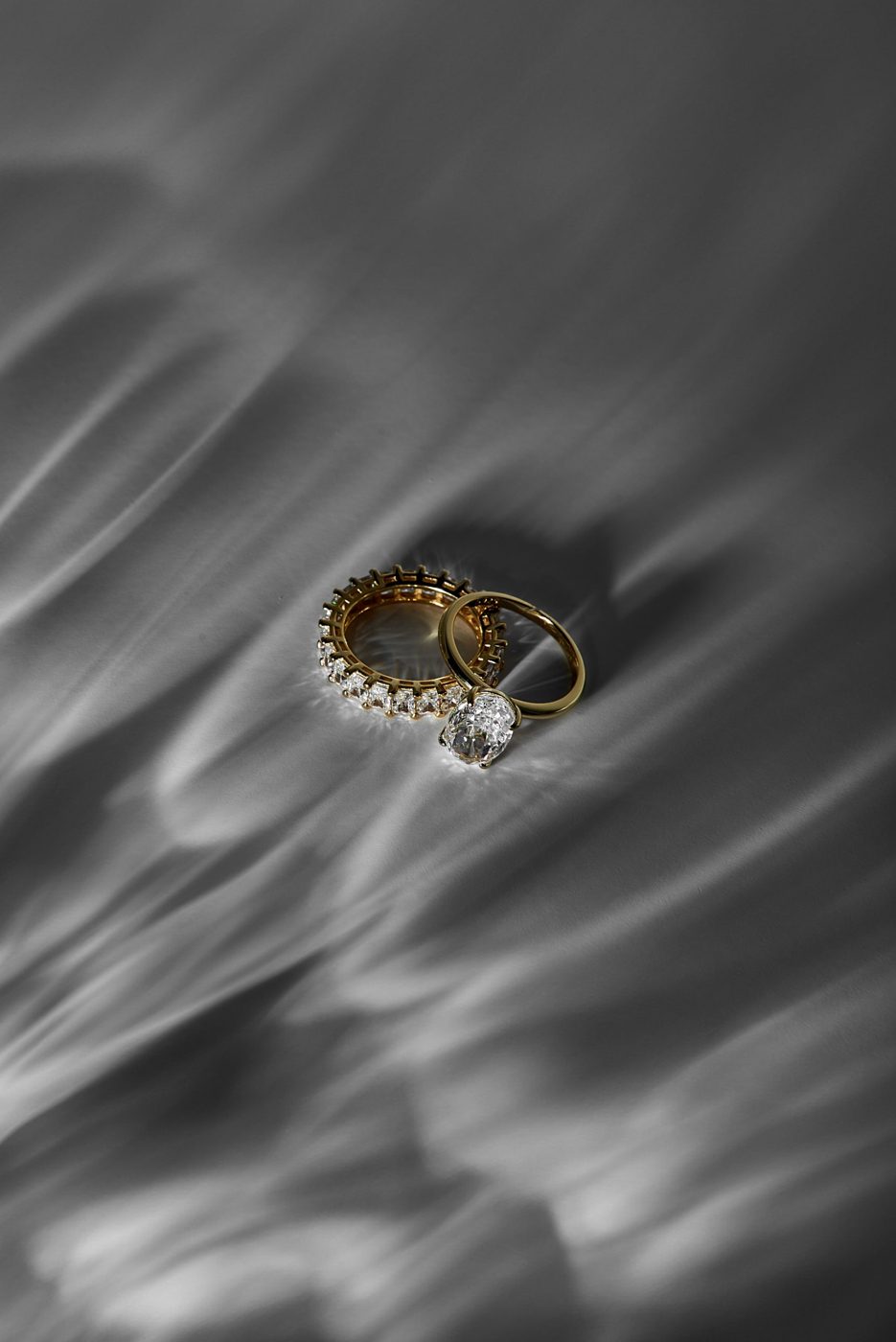 An oval diamond solitaire and eternity band in yellow gold in rippling light